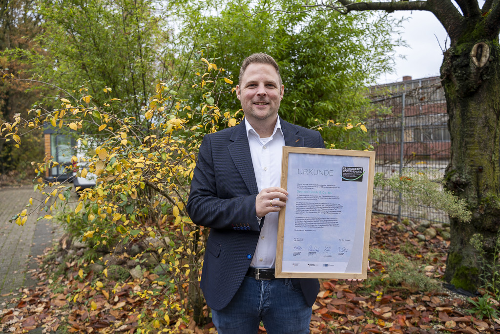 Mann hält Urkunde im Freien, symbolisiert Nachhaltigkeit bei SPALECK.