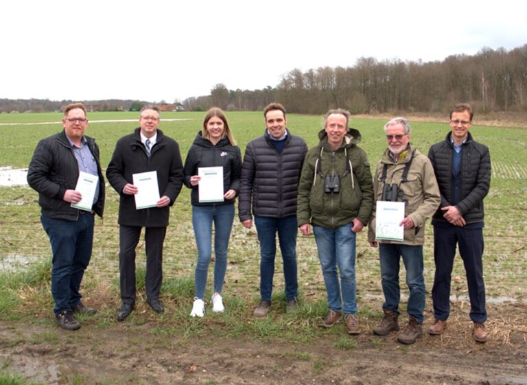 Gruppe von Menschen auf einem Feld zeigt Dokumente, Nachhaltigkeit bei SPALECK.