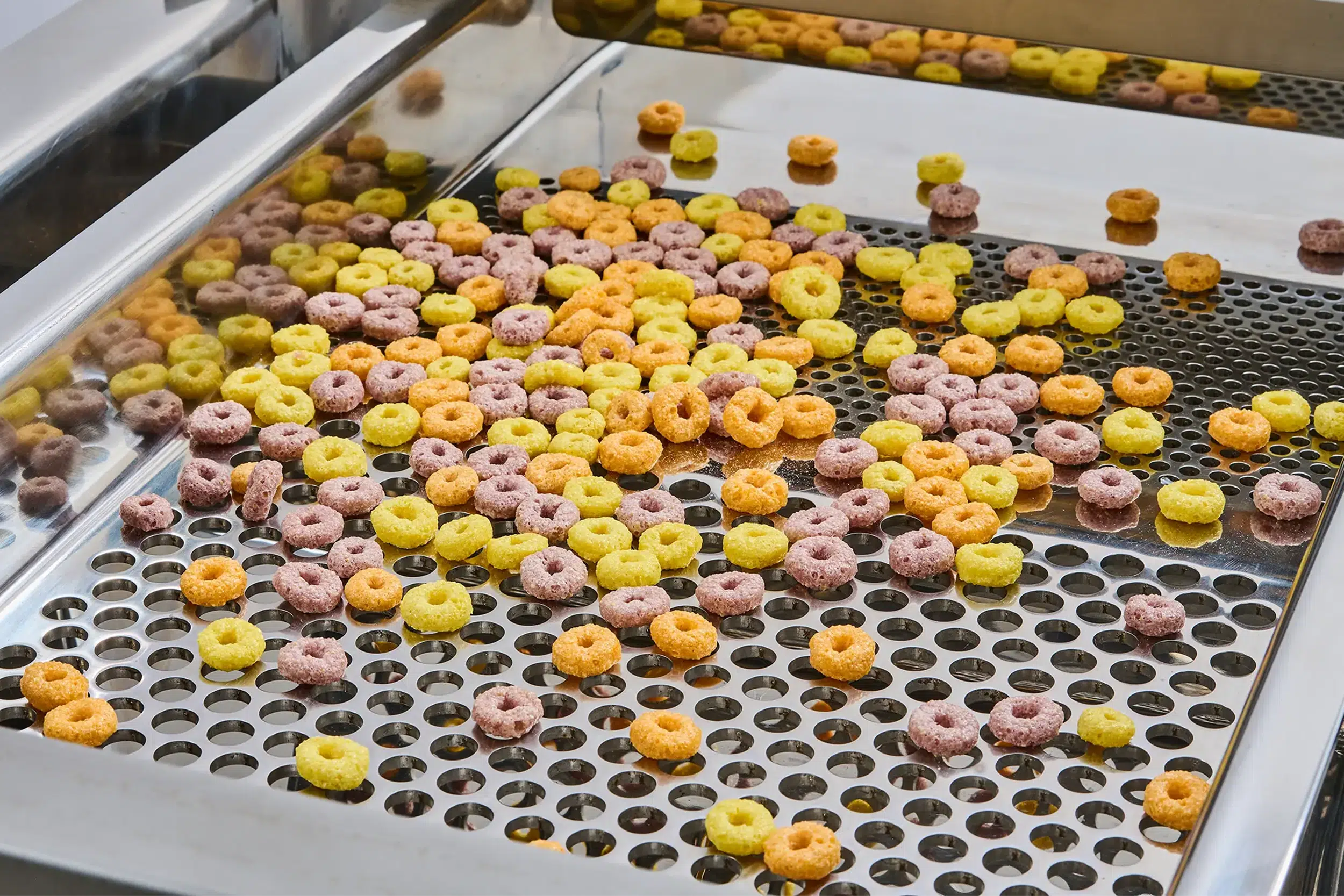 食品篩分機將五顏六色的穀物圈分篩到篩網上。