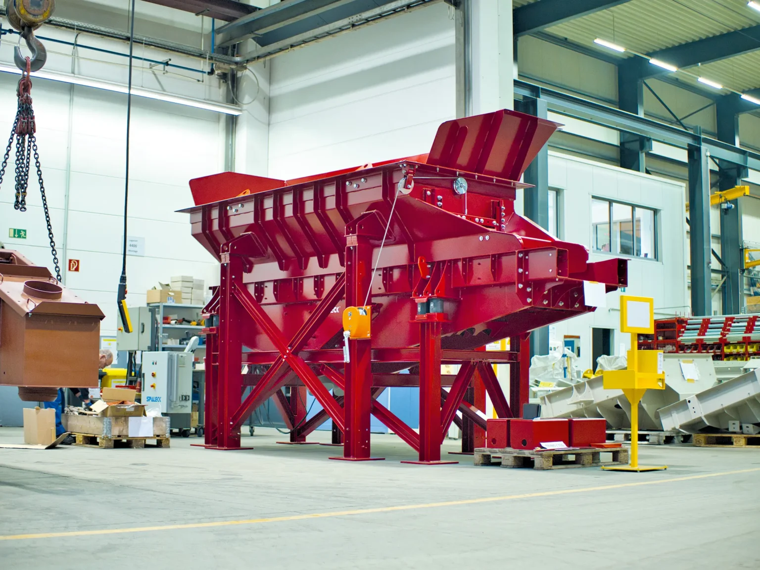 Red Infeed hopper in the production area at SPALECK, a manufacturer of Recycling technology. This Infeed hopper is used in slag processing to feed material into the Recycling process.