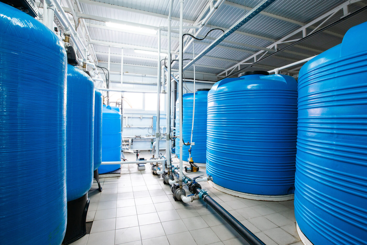 Mehrere große blaue Tanks zur Fällung und Flockung in der Wasseraufbereitung in Industriehalle