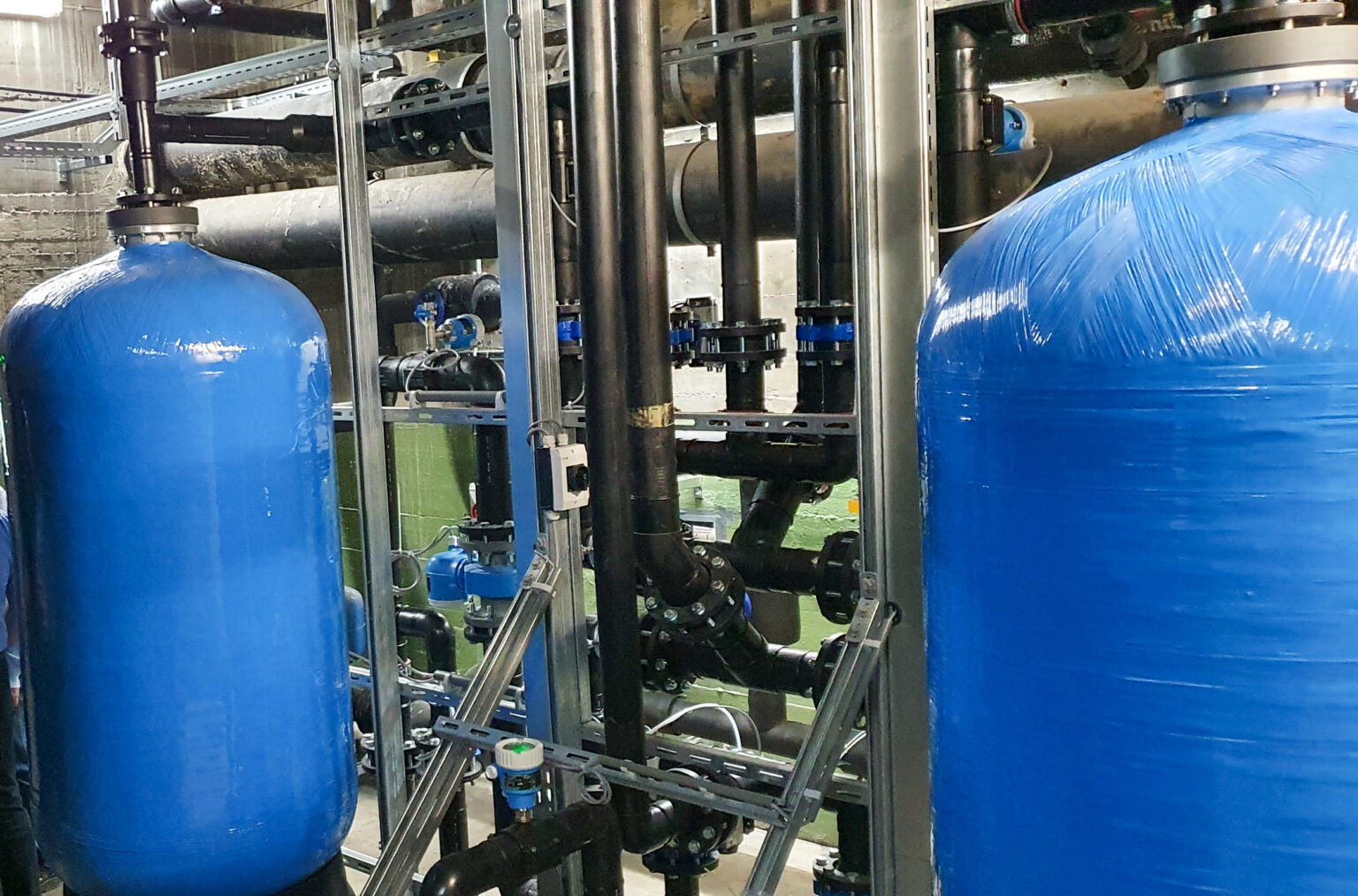 Sandfiltrationsanlage mit zwei blauen Tanks und Verrohrung zur industriellen Wasseraufbereitung.