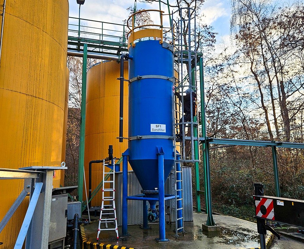 Blauer Tank zur Sandfiltration in der Wasseraufbereitung neben gelben Tanks.