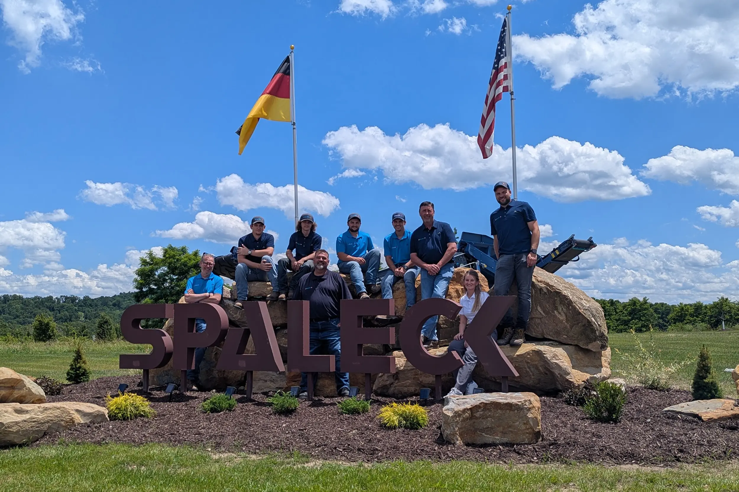 Gruppe von Menschen vor dem SPALECK-Schild mit deutschen und US-amerikanischen Flaggen.